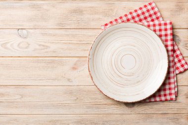 Renkli arka planda üst görünüm yiyecek için masa örtüsü üzerindeki boş yuvarlak beyaz tabak. Tasarımınız için boşluk olan peçeteye boş tabak.