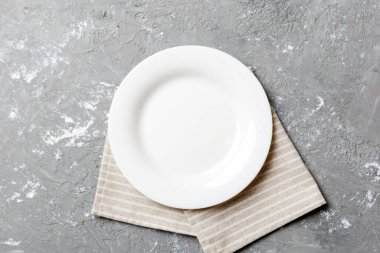 Renkli arka planda üst görünüm yiyecek için masa örtüsü üzerindeki boş yuvarlak beyaz tabak. Tasarımınız için boşluk olan peçeteye boş tabak.