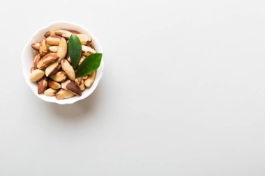 Fresh healthy Brazil nuts in bowl on colored table background. Top view Healthy eating bertholletia concept. Super foods.