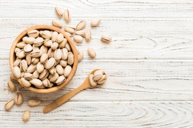 Fresh healthy Pistachios in bowl on colored table background. Top view. Healthy eating concept. Super foods.