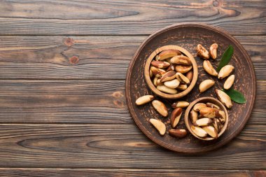 Fresh healthy Brazil nuts in bowl on colored table background. Top view Healthy eating bertholletia concept. Super foods.