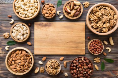 mixed nuts in wooden bowl. Mix of various nuts on colored background. pistachios, cashews, walnuts, hazelnuts, peanuts and brazil nuts.