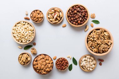 mixed nuts in wooden bowl. Mix of various nuts on colored background. pistachios, cashews, walnuts, hazelnuts, peanuts and brazil nuts.