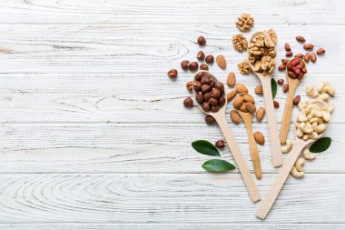 mixed nuts in white wooden spoon. Mix of various nuts on colored background. pistachios, cashews, walnuts, hazelnuts, peanuts and brazil nuts.