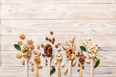 mixed nuts in white wooden spoon. Mix of various nuts on colored background. pistachios, cashews, walnuts, hazelnuts, peanuts and brazil nuts.