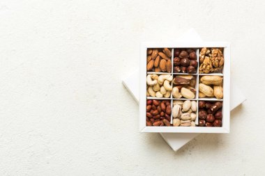 Various varieties of nuts lying in paper box on table background. Top view. Healthy food. Close up, copy space, top view, flat lay. Walnut, pistachios, almonds, hazelnuts and cashews.