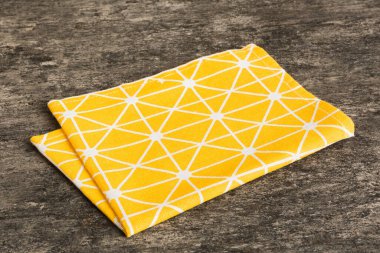 top view with yellow empty kitchen napkin isolated on table background. Folded cloth for mockup with copy space, Flat lay. Minimal style.