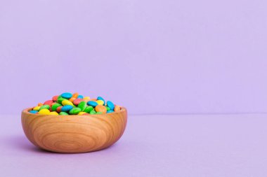 Renkli arka planda bir kasede çok renkli şekerler. Doğum günü ve tatil konsepti. Kopyalama alanı olan üst görünüm.
