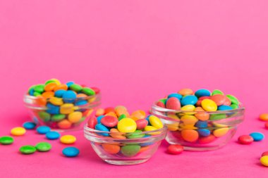 Renkli arka planda bir kasede çok renkli şekerler. Doğum günü ve tatil konsepti. Kopyalama alanı olan üst görünüm.