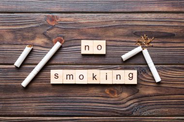 Sigara ve tahta bloklar, masa arkasında kırık sigara kum saati ile tütün günü yok, saat sağlığı konsepti. Sigarayı bırakma zamanı..