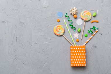 gift box in corner full of assorted traditional candies falling out on colored background with copy space. Happy Holidays sale concept.