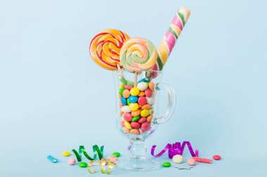 Masanın üzerinde açık arkaplanda renkli şekerler. Büyük kıvrımlı lolipoplar. Şekerci dükkanından leziz şekerlerle dolu yaratıcı bir kavanoz konsepti.