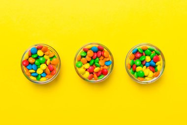 Renkli arka planda bir kasede çok renkli şekerler. Doğum günü ve tatil konsepti. Kopyalama alanı olan üst görünüm.