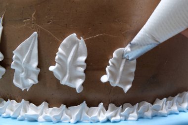 Elinde pasta poşeti olan bir kadın pasta şefi ev mutfağında pastaya krema sıkıyor. Fırın mutfağında çalışan profesyonel bir şef. Yemek pişirme, yemek pişirme, ev yemeği..