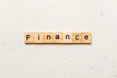 Tahta bloğa yazılmış finans sözcüğü. Deksing, konsept için çimento üzerinde FINANCE metin.