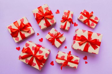 Top view photo of valentine day decorations gift box with red ribbon bow on colored background. Holiday gift boxes with top view.