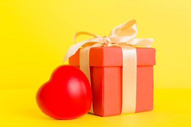 gift box with red bow and red heart on colored background. Perspective view. Flat lay.