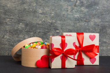 Valentine day composition: sweet candy, with gift boxes with bow and red felt hearts, photo template, background. Perspective with copy space.