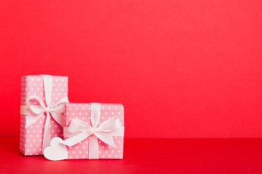 gift box with red bow and red heart on colored background. Perspective view. Flat lay.