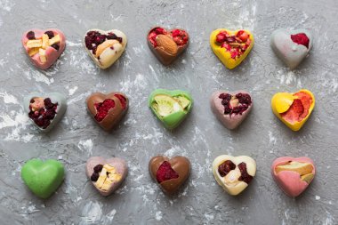 chocolate sweets in the form of a heart with fruits and nuts on a colored background. top view with space for text, holiday concept.