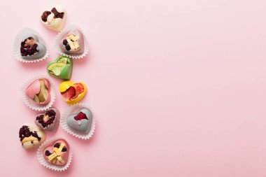 chocolate sweets in the form of a heart with fruits and nuts on a colored background. top view with space for text, holiday concept.