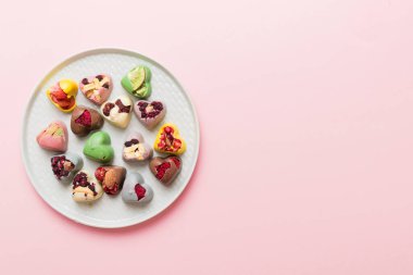 Plate with different chocolate on colored background. Assortment of fine chocolates top view vith copy space Health and obesity concept.