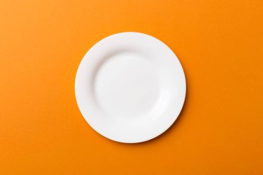 Renkli arka plan görüntüsünün üst görüntüsü yiyecek için boş yuvarlak beyaz tabak. Tasarımınız için alanı olan boş tabak.