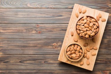Fresh healthy Almond in bowl on colored table background. Top view.