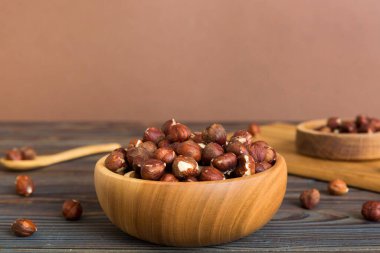 Wooden bowl full of hazelnuts on table background. Healthy eating concept. Super foods.