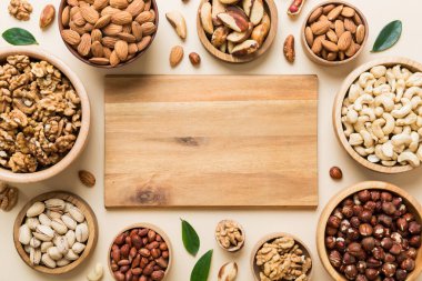 mixed nuts in wooden bowl. Mix of various nuts on colored background. pistachios, cashews, walnuts, hazelnuts, peanuts and brazil nuts.