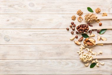 mixed nuts in white wooden spoon. Mix of various nuts on colored background. pistachios, cashews, walnuts, hazelnuts, peanuts and brazil nuts.