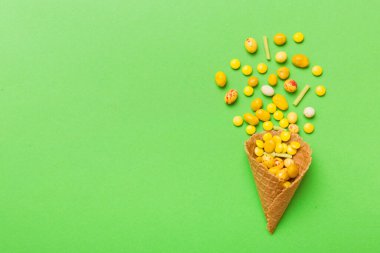 waffle cone full of assorted traditional candies falling out on colored background with copy space. Happy Holidays sale concept.