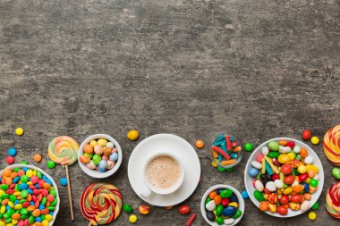 Coffee cup with chocolates and colored candy. Top view on table background with copy space.