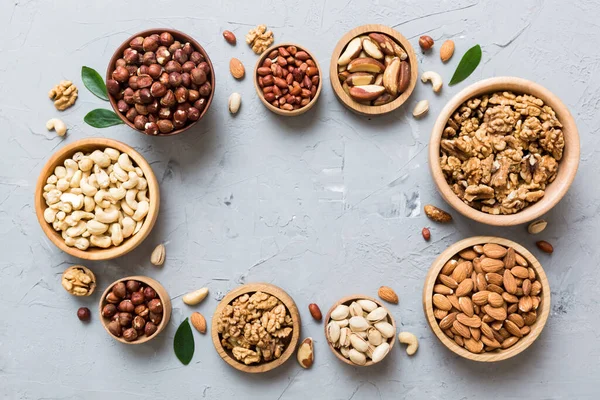mixed nuts in wooden bowl. Mix of various nuts on colored background. pistachios, cashews, walnuts, hazelnuts, peanuts and brazil nuts.