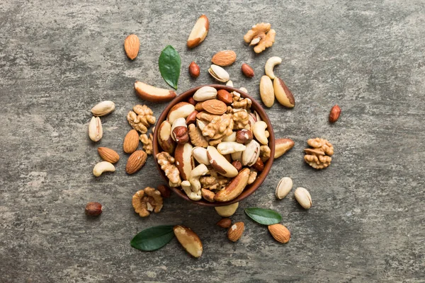 mixed nuts in bowl. Mix of various nuts on colored background. pistachios, cashews, walnuts, hazelnuts, peanuts and brazil nuts.