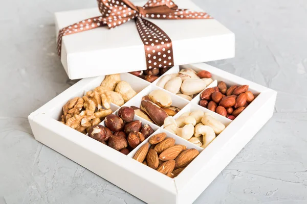 Various varieties of nuts lying in paper box on table background. Top view. Healthy food. Close up, copy space, top view, flat lay. Walnut, pistachios, almonds, hazelnuts and cashews.