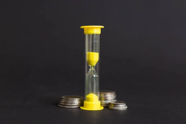 Deadline and time is money concept with hourglass and US coins currency. sand clock time for saving concept.