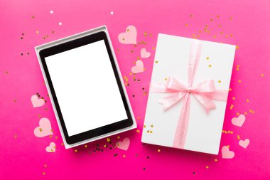 Gift box of open tablet for the holidays with a bow top view.