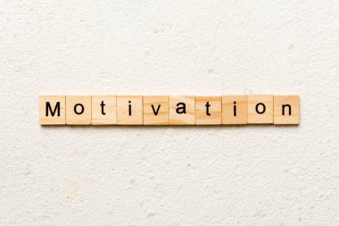 Tahta blokta yazan motivasyon kelimesi. Deksing, konsept için çimento masadaki motivasyon metni.