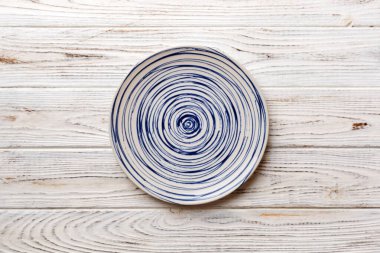 Ahşap zemindeki boş renkli tabağın üst görünümü. Tasarımın için boş boşluk.