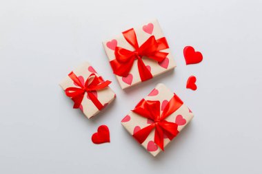 Top view photo of valentine day decorations gift box with red ribbon bow on colored background. Holiday gift boxes with top view.