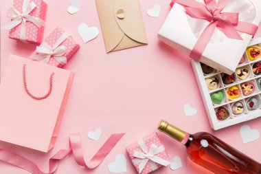 top view photo of st valentine day decor shopping, bag, wine, bottle, envelope, gift, box, candy and red heart on colored background with empty space. Frame background.