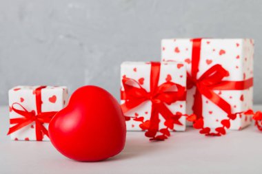 gift box with red bow and red heart on colored background. Perspective view. Flat lay.