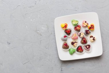 Plate with different chocolate on colored background. Assortment of fine chocolates top view vith copy space Health and obesity concept.