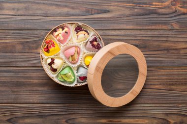Holiday composition: sweet candy, with gift boxes with bow and chocolate hearts, photo template, background. Top View with copy space on colored background.