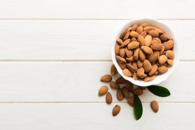 Fresh healthy Almond in bowl on colored table background. Top view.