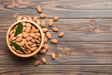 Fresh healthy Almond in bowl on colored table background. Top view.