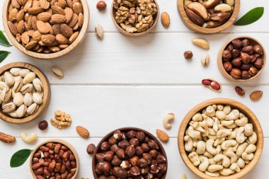 mixed nuts in wooden bowl. Mix of various nuts on colored background. pistachios, cashews, walnuts, hazelnuts, peanuts and brazil nuts.