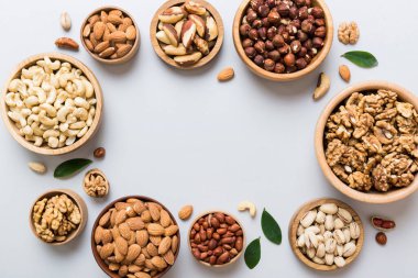 mixed nuts in wooden bowl. Mix of various nuts on colored background. pistachios, cashews, walnuts, hazelnuts, peanuts and brazil nuts.