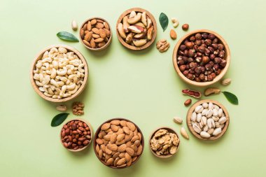 mixed nuts in wooden bowl. Mix of various nuts on colored background. pistachios, cashews, walnuts, hazelnuts, peanuts and brazil nuts.